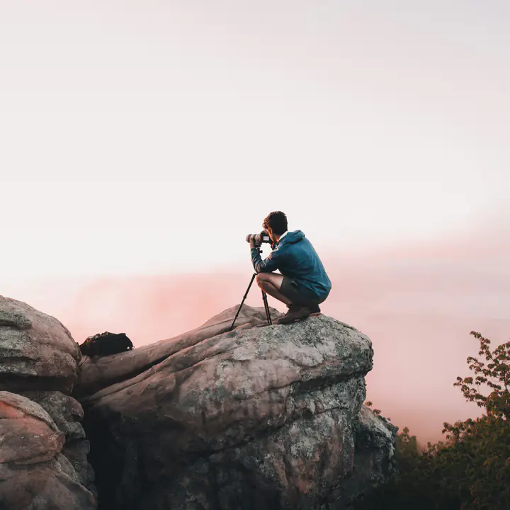 A traveler photographing a valley at sunrise